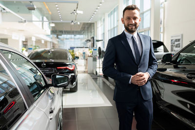 Portrait of businessman standing in car showroom