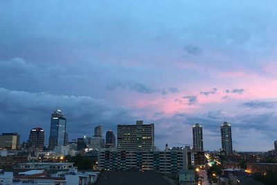 Illuminated buildings in city against sky at sunset