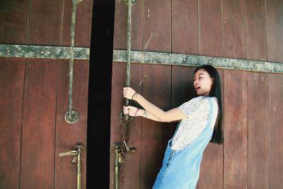 Side view of woman opening wooden door