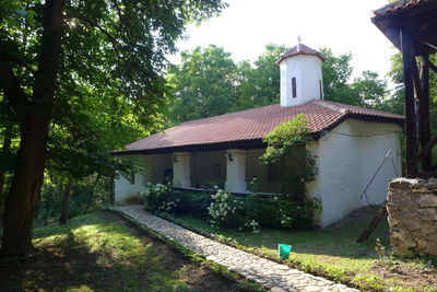 House amidst trees and buildings against sky