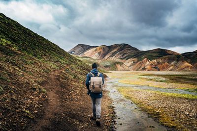 Rear view of man standing on landscape against sky