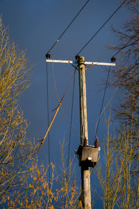 Low angle view of telephone pole against clear blue sky