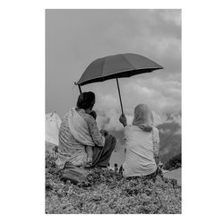 People sitting on rock against sky