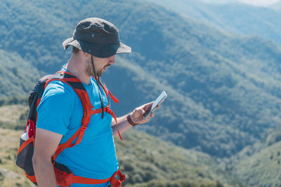 Young man using mobile phone against mountain