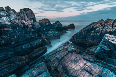 High angle view of rock formations in sea against cloudy sky during sunset