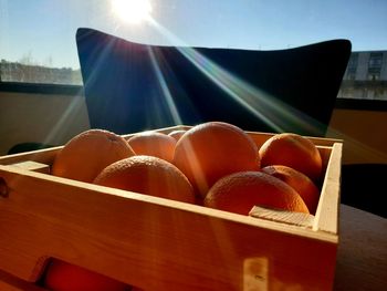 Close-up of orange fruits in container on sunny day