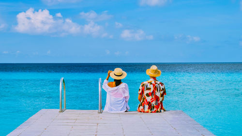 Rear view of people at beach against sky