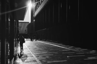 Rear view of man walking on walkway by building