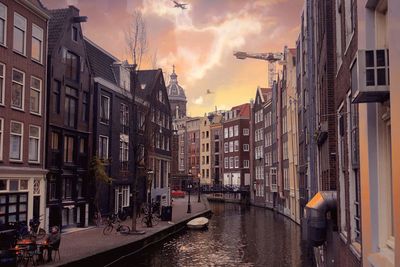 Canal amidst buildings against sky during sunset