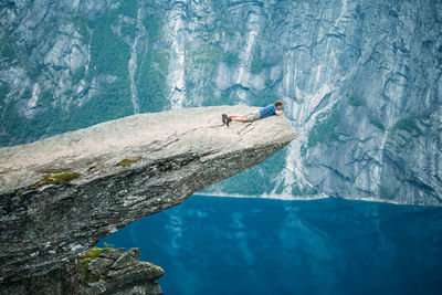 Man lying on cliff by sea