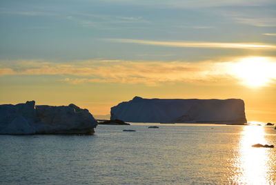 Scenic view of sea against clear sky with beautiful icebergs in the midnight sun ilulissat greenland