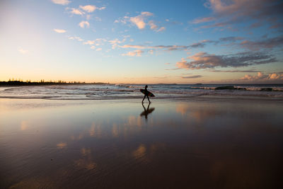 Silhouette man on beach against sky during sunset