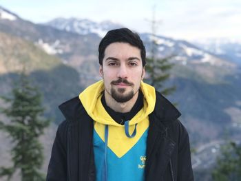 Portrait of young man standing against mountain