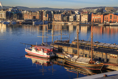 Boats moored in river by buildings in city