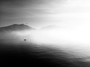 Scenic view of lake by silhouette mountain against sky