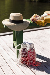 Bottles in net bag and straw hat on jetty