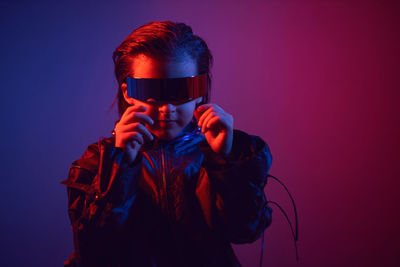 Portrait cyberpunk boy child in vr glasses in blue and red tones. game, virtual reality