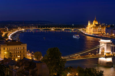 Illuminated bridge over river in city at night