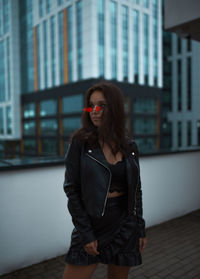 Portrait of young woman wearing sunglasses while standing in city