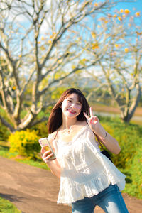 Young woman standing against trees