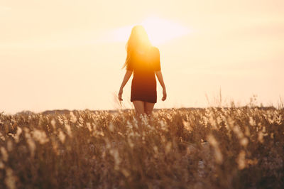 Woman walking on grassy field during sunny day