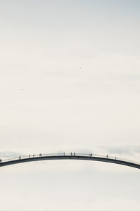 Bridge against sky with people and families crossing 