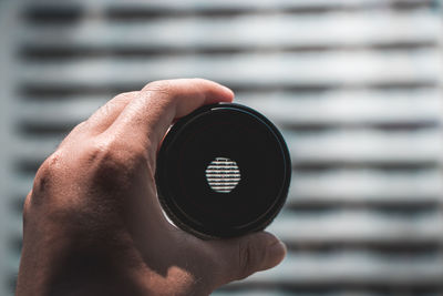 Cropped hand holding lens against blinds