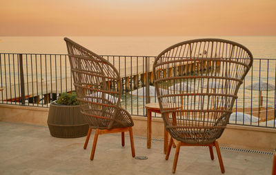 Empty wicker chairs and table with sea and sunset views.