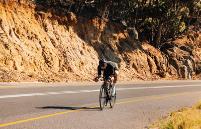 Rear view of man riding bicycle on road