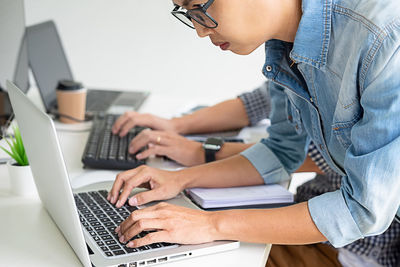 Midsection of woman using mobile phone while sitting on table