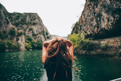 Rear view of woman standing in lake against sky