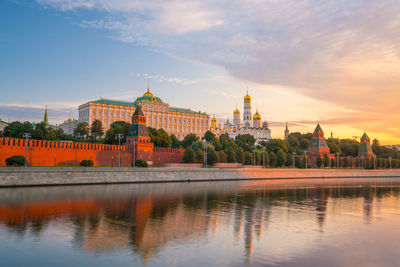 Buildings at waterfront against cloudy sky