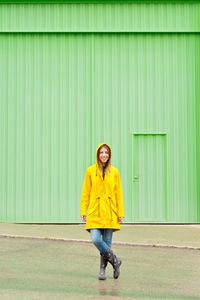 Portrait of young woman standing against wall