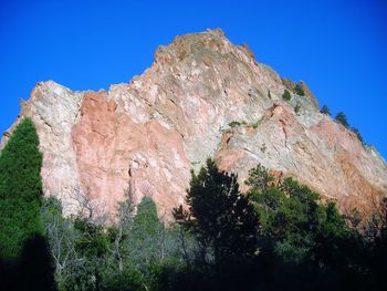 Low angle view of rocks against clear blue sky