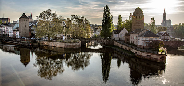 Panoramic view of buildings by river against sky in city