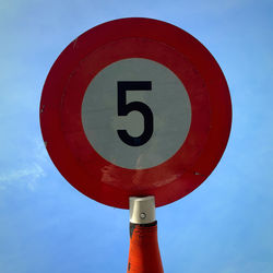Low angle view of road sign against blue sky