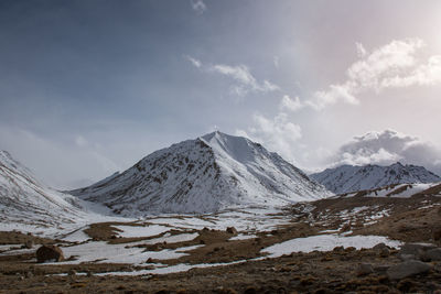 Scenic view of snowcapped mountains against cloudy sky