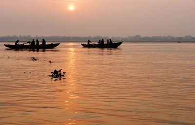 Silhouette boats in sea against sky during sunset