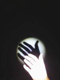 Close-up of hand holding illuminated light against black background
