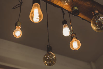 Low angle view of illuminated light bulb hanging from ceiling