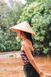 Side view of woman standing by wet umbrella during rainy season