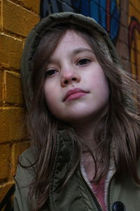 Close-up portrait of girl against painted brick wall