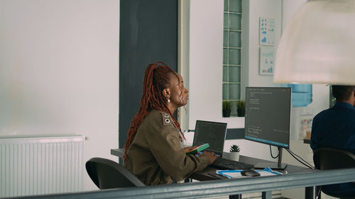 Side view of young woman using digital tablet while sitting at home