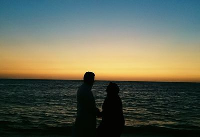 Silhouette of people in sea at sunset