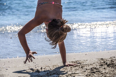 Woman doing handstand on beach