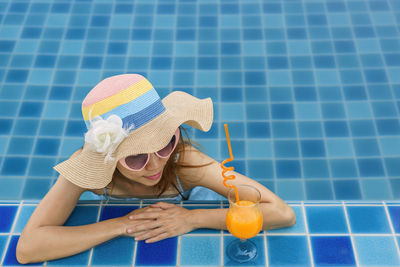 Midsection of woman wearing hat against swimming pool