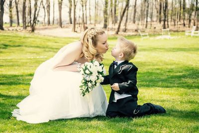 Bride and son puckering lips on grassy field during wedding