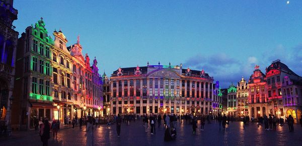 People by illuminated grand place at dusk