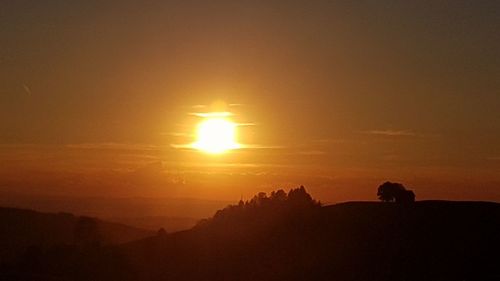 Scenic view of silhouette landscape against orange sky