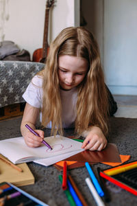 Portrait of young woman writing in book at home